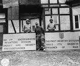 Sgt. Mallory J. Kocopina, W. Aliquippa, PA & Sgt. Worner W. Kahl, Detroit MI., Put out a welcome sign for the 100,000th prisoner taken by the 1st Division, U.S. First Army. Sgt. Mallory J. Kocopina, W. Aliquippa, PA & Sgt. Worner W. Kahl, Detroit MI., Put out a welcome sign for the 100,000th prisoner taken by the 1st Division, U.S. First Army.